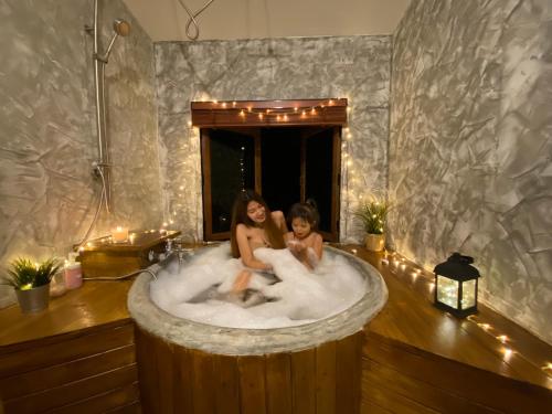 Ban Noen Sombunเติมเต็มคาเฟ่&แคมป์ปิ้ง by สวนเขาจุก的两个女孩坐在浴缸里,沐浴着灯光