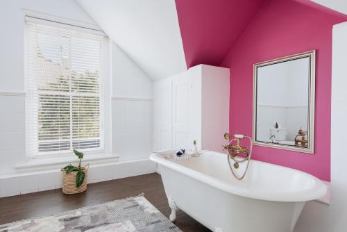 斯泰伦博斯River Manor Boutique Hotel by The Living Journey Collection的粉红色的浴室设有浴缸和镜子
