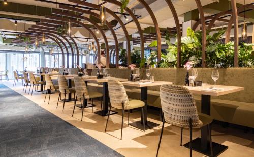 马克内瑟Fletcher Hotel-Restaurant Marknesse的一间设有桌椅的餐厅,种植了植物