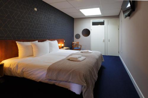 Wirdum杜霍克斯酒店的一间卧室配有一张带白色床单的大床