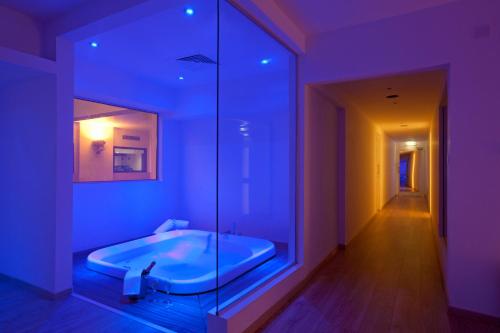 拉纳卡Sandy Beach Hotel & Spa - ex Sentido的浴室配有紫色照明的浴缸