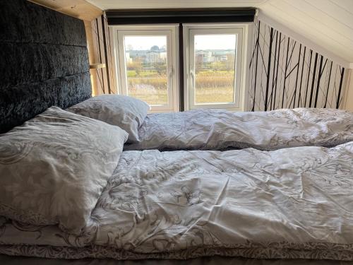 查珀尔圣伦纳兹Chapel Fields Holiday Park的卧室设有一张未铺床,设有2个窗户。