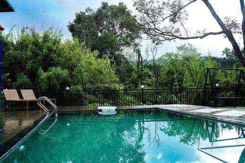 维特利Caravan holiday homes Vythiri的一个带黑色围栏和树木的游泳池