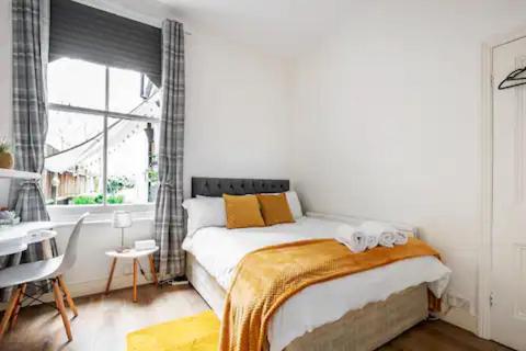 伦敦Alross Room with Breakfast的一间卧室配有一张床、一张书桌和一个窗户。