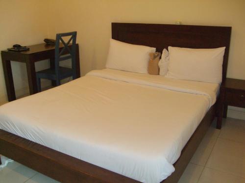 芭堤雅市中心班齐提玛公寓的一间卧室配有一张带白色床单的床和一张书桌。