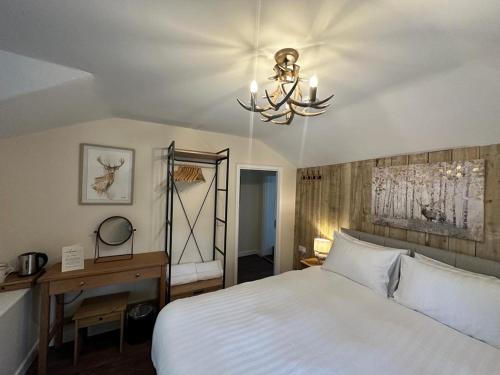 林德赫斯特The New Forest Inn的卧室配有一张白色大床和吊灯。