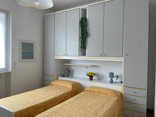 韦尔巴尼亚Il nido del merlo Parcheggio e giardino的卧室设有2张床和白色橱柜。