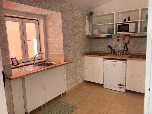 塞图巴尔5 Senses Hostel的厨房配有白色橱柜和水槽