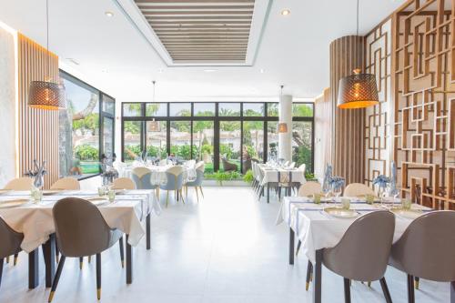 哈维亚Hotel Casa Lili的餐厅设有白色的桌椅和大窗户。