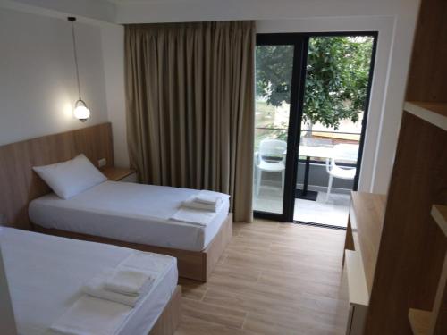 卡萨米尔Hotel Ksamili的酒店客房,设有两张床和滑动玻璃门