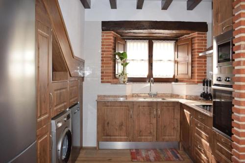 SelayaCasa Rural Los Riveros de Jeromo的厨房配有木制橱柜、水槽和窗户。