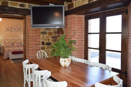SelayaCasa Rural Los Riveros de Jeromo的一间带木桌和白色椅子的用餐室