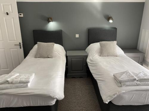 北安普敦The Roade House的配有2张床的带白色床单和枕头的客房