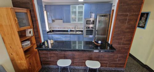 塔马达斯特VV EL OASIS的厨房配有柜台和2把白色椅子