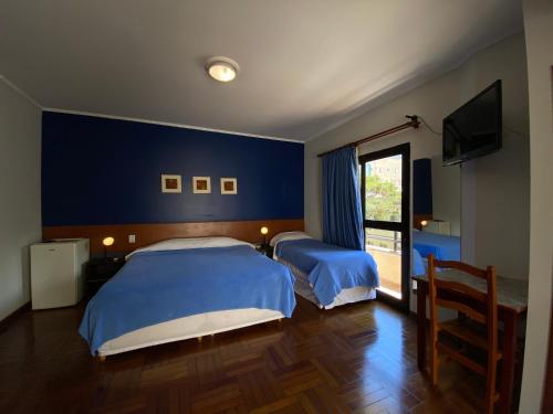 波苏斯-迪卡尔达斯米纳斯花园酒店的卧室设有两张床铺,拥有蓝色的墙壁