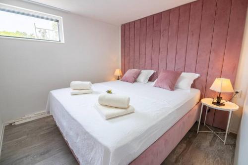 RogačićPerina Haven - Island Vis Beachfront的卧室配有白色大床和粉红色的墙壁