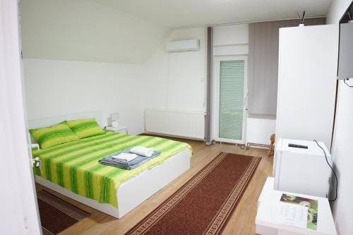 克拉多沃Rooms Busujok的一间卧室配有一张带绿色和黄色毯子的床