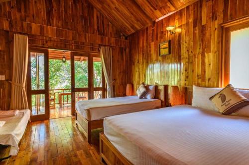 富国芒果海滩度假酒店的一间带两张床铺的卧室,位于带木墙的房间内