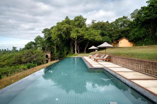 本托塔Lunuganga Estate的一个带长凳的游泳池,位于田野旁