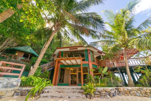 爱妮岛Kudugman Beach Cottages - El Nido的棕榈树海滩上的房子