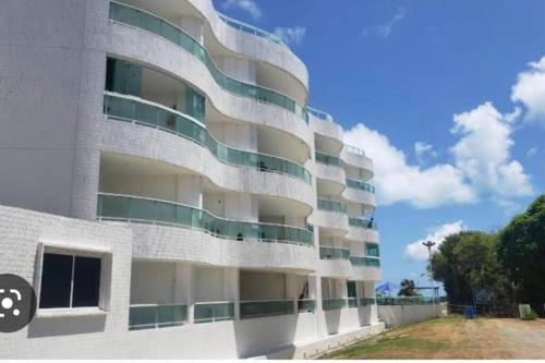康德Flat Beira Mar Carapibus的白色的建筑,设有绿色和白色的阳台