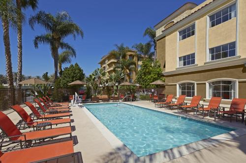 安纳海姆阿纳海姆酒店波托菲诺套房酒店的一座带椅子的游泳池以及一座建筑