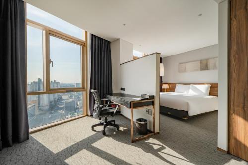 蔚山Staz Hotel Ulsan的酒店客房设有一张床、一张书桌和窗户。