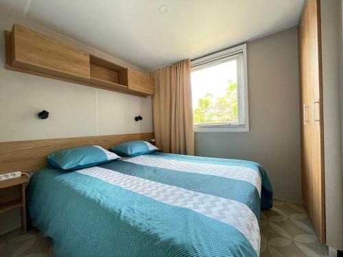拉特斯Camping le lac des rêves L'ABRIZEN的一间卧室配有一张带蓝色枕头的床和一扇窗户。