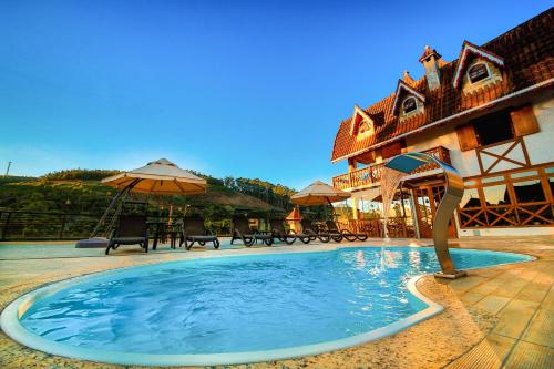 蒙特韦尔迪洛斯维第斯旅馆的一座带遮阳伞的建筑前的游泳池