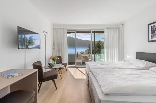 阿斯科纳Casa Berno Panorama Resort的酒店客房带一张床、一张桌子和椅子