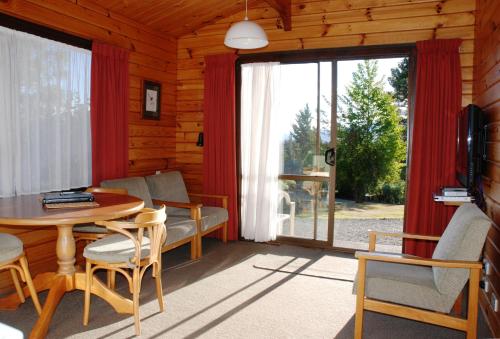 汉默温泉小木屋汽车旅馆的客厅配有桌椅和大窗户