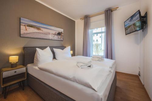 赛巴特班森Haus Strandoase 27的卧室配有一张大白色床和窗户