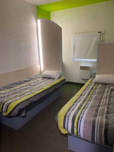 圣洛HOTEL F1 SAINT-LO的客房设有两张床和窗户。