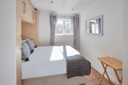 惠特比Apartment 2, Khyber Lodge Apartment Whitby的卧室配有白色的床和窗户。