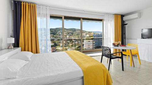 曼德琉-拉纳普勒Cannes Marina Appart Hotel Mandelieu的一间卧室配有一张床和一张桌子,享有美景
