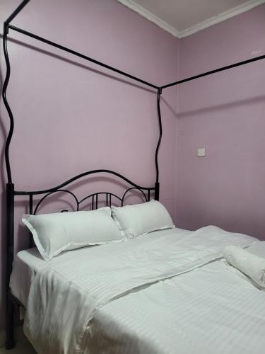 纳库鲁G&G Homes Naka Nakuru的一张带黑色框架和白色床单及枕头的床