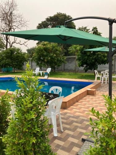 Amphoe Sawang Daen DinANGEL RESORT i的一个带绿色遮阳伞和椅子的庭院和一个游泳池