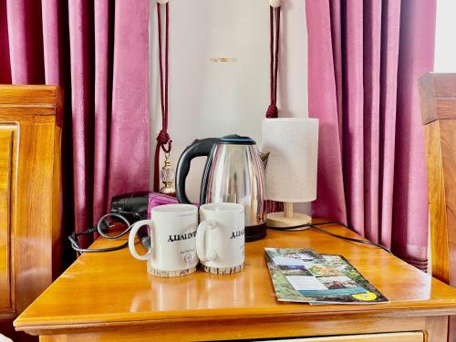 峰牙Phong Nha - Tien's Cozy Homestay的一张桌子,上面有咖啡壶和两个杯子