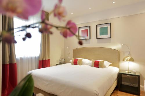 钱皮诺别墅套房酒店的一间卧室配有白色床单和粉红色鲜花。