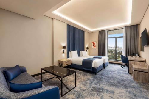 巴库Wyndham Garden Baku的酒店客房配有床、沙发和电视。