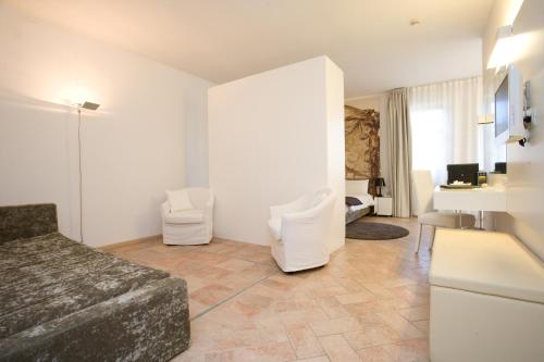 Santa Vittoria dʼAlba迪圣塔维多利亚城堡酒店的客厅配有床和两把白色椅子