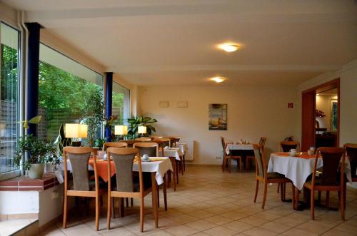 沃尔夫斯堡爱姆科里维斯伯格酒店的餐厅设有桌椅和大窗户。