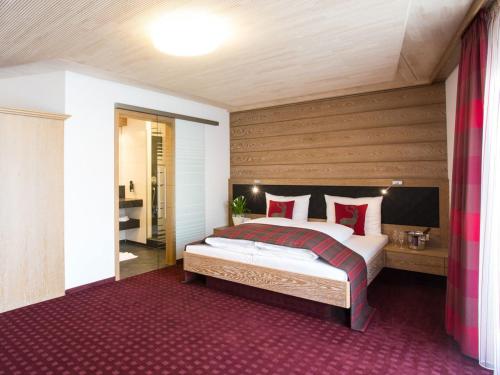 加默廷根克罗伊茨旅馆的一间卧室配有一张带红色枕头的大床