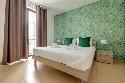 斯利马Sliema Tigne Suites的一间卧室配有一张带绿色壁纸的大床