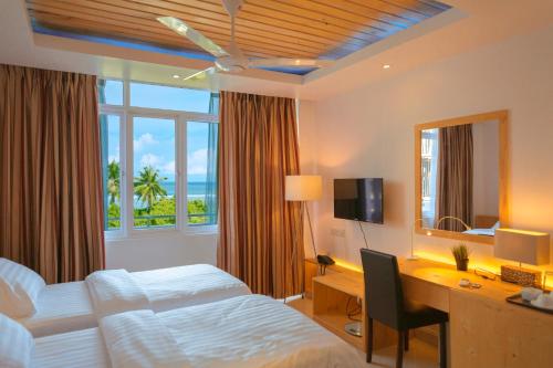 胡鲁马累PINE LODGE MALDIVES的酒店客房配有一张床、一张书桌和一台电脑