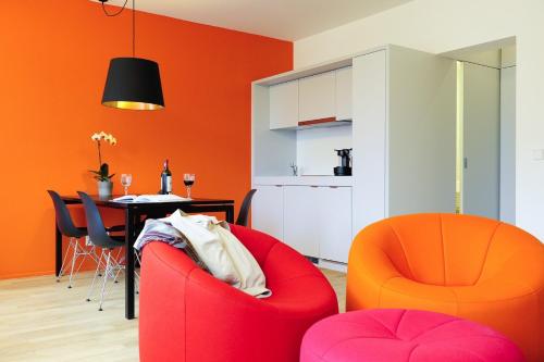 卢森堡凯帕克德梅尔公寓酒店的客厅配有橙色椅子和桌子