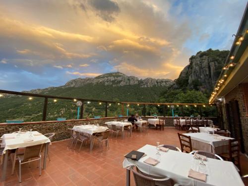 多尔加利Hotel Sant'elene的餐厅设有桌子,后方是一座山。