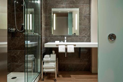 明尼阿波利斯明尼阿波利斯市中心万豪AC酒店的一间带水槽和玻璃淋浴的浴室
