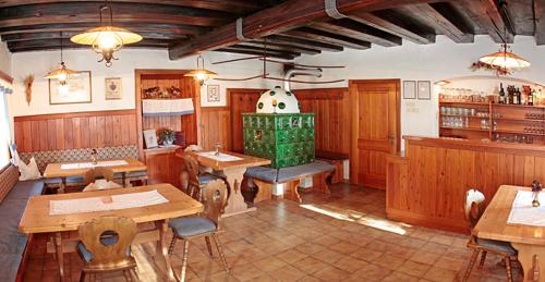 萨菲登安斯泰内嫩米尔Pension Schmiderer - Vorderkasbichlhof的餐厅设有木桌、椅子和绿色炉灶。
