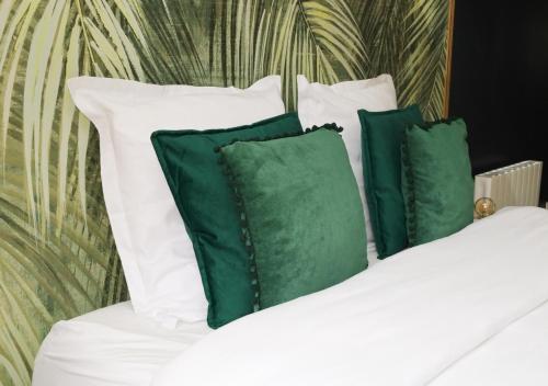 埃夫勒L’Esmeralda Spa ancien garage devenu suite luxueuse的一张带白色枕头和绿色枕头的床